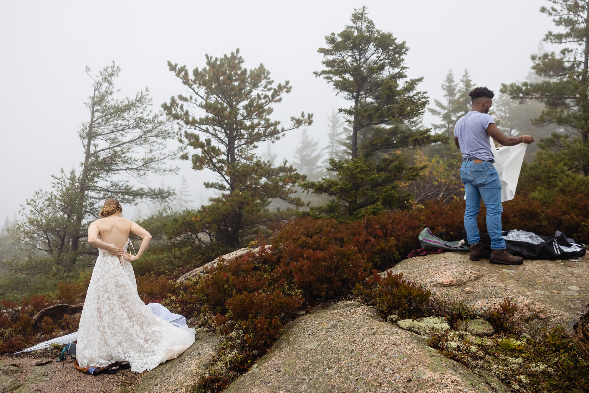 A wedding couple change into their wedding clothes on a mountain in Acadia National Park for their elopement
