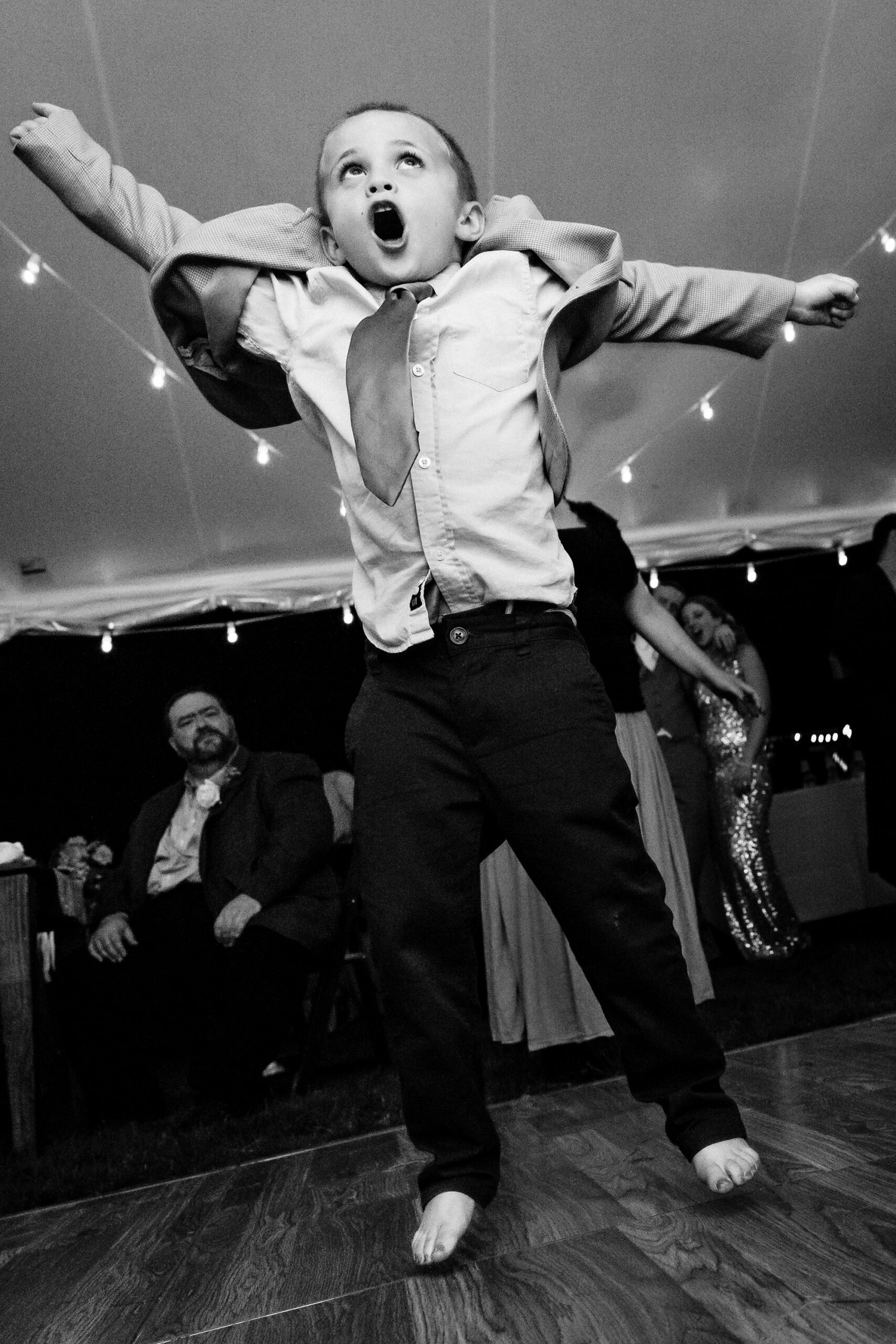A boy jumps for joy at a Maine wedding.