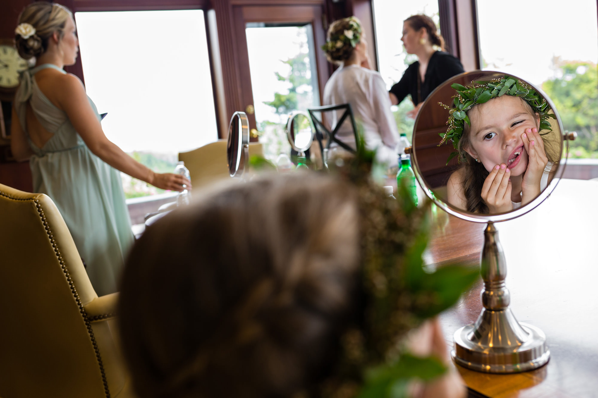 A flower girl pulls funny faces while getting ready for a wedding.