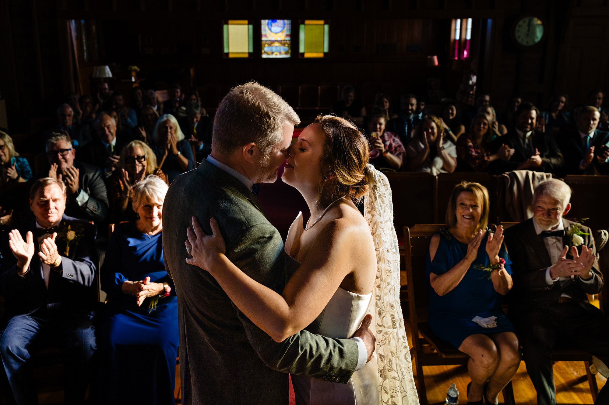 A bride and groom kiss in a chapel on their wedding day.