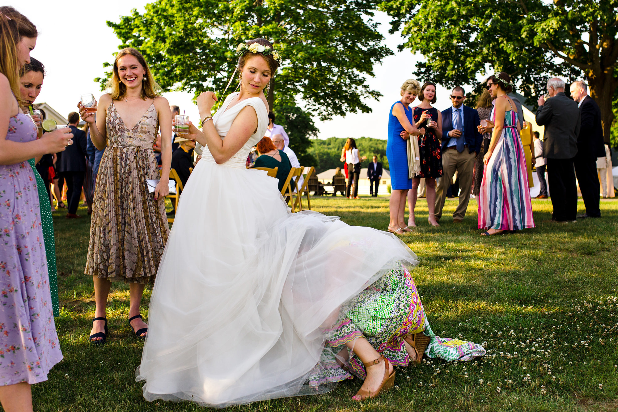 A friend helps the bride with her bustle during cocktail hour, making her look like a centaur.