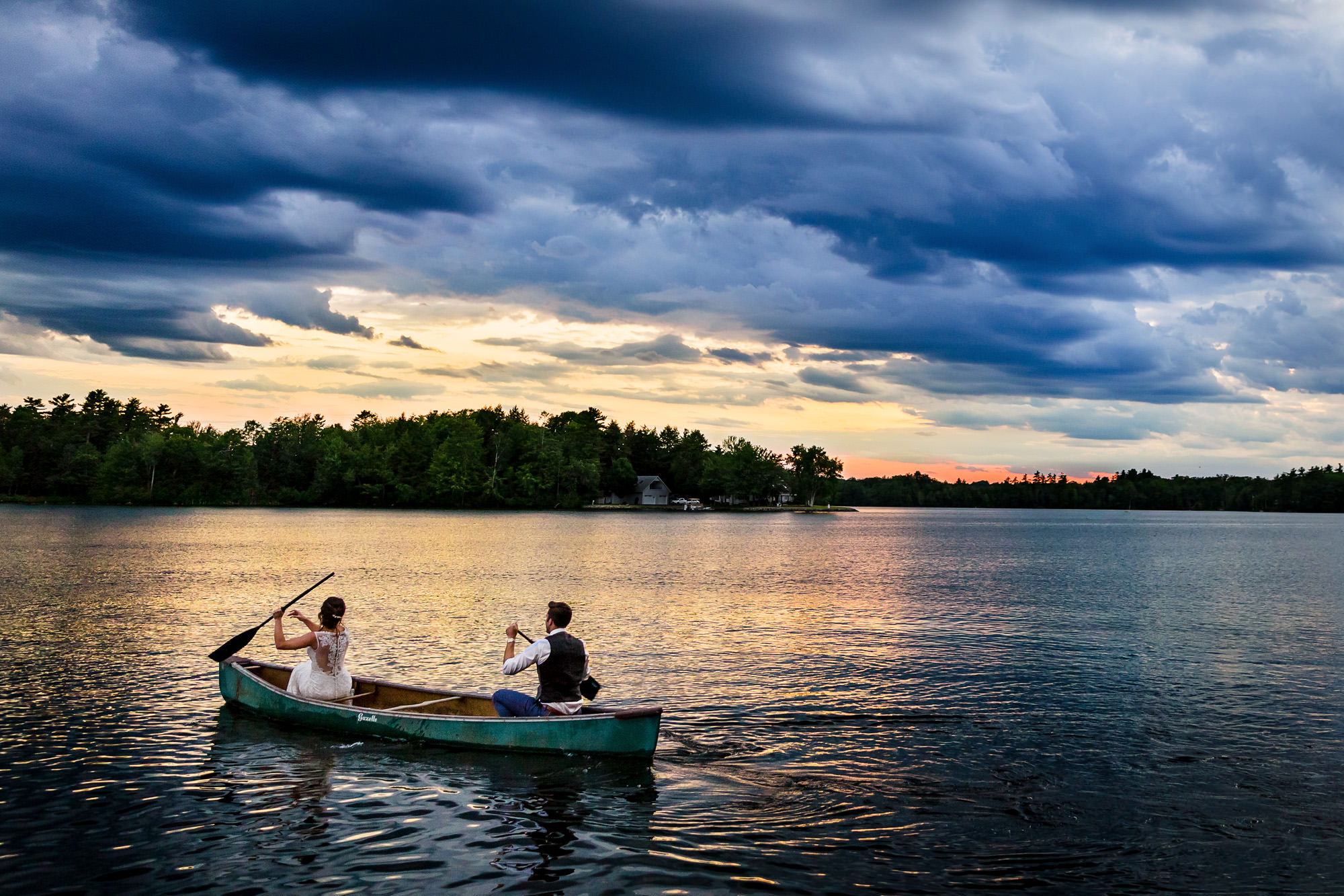 A romantic couple in a canoe, surrounded by a serene lake at sunset, on their special day.
