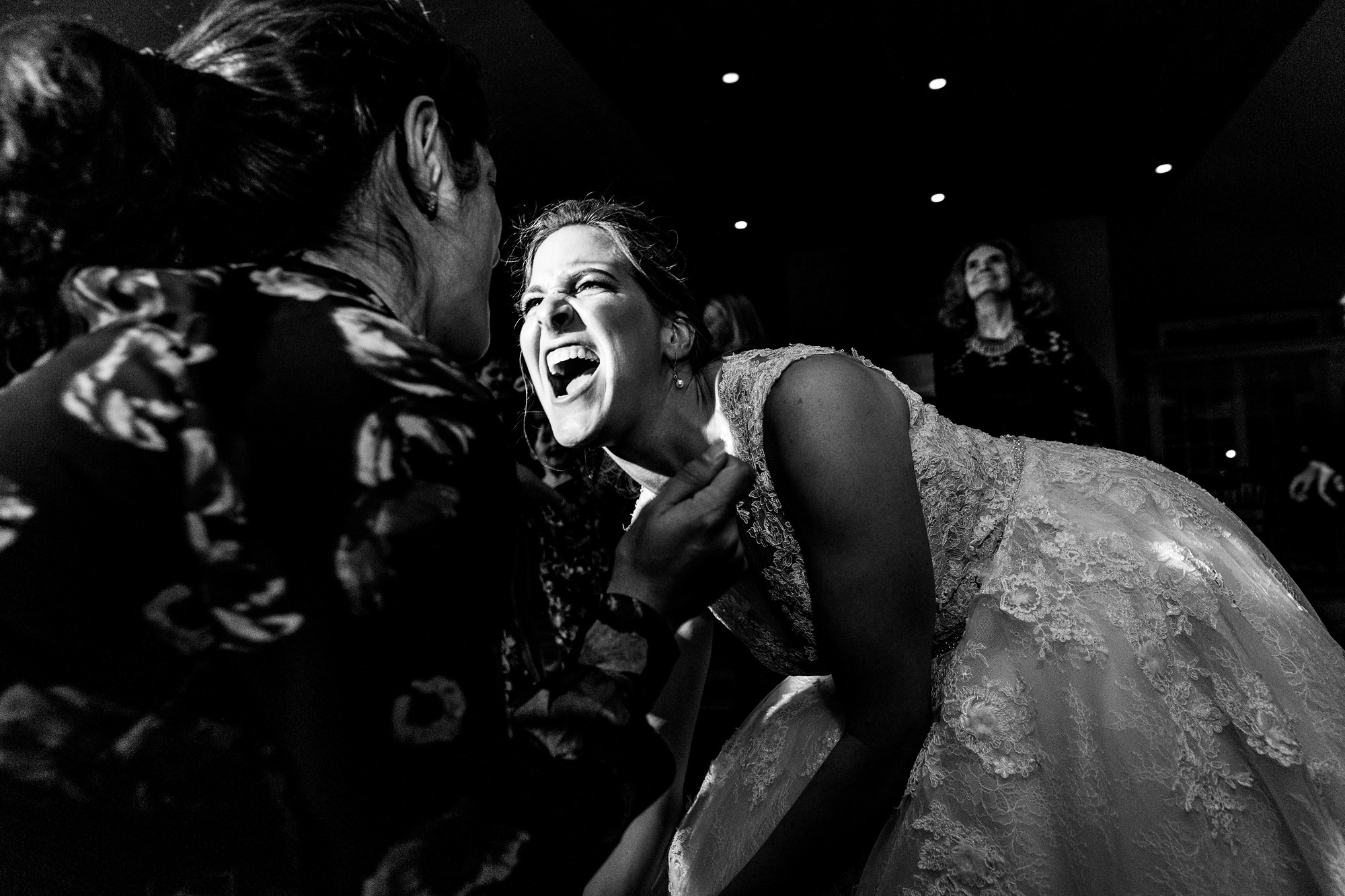 The bride and her friend dance rigorously at her wedding.