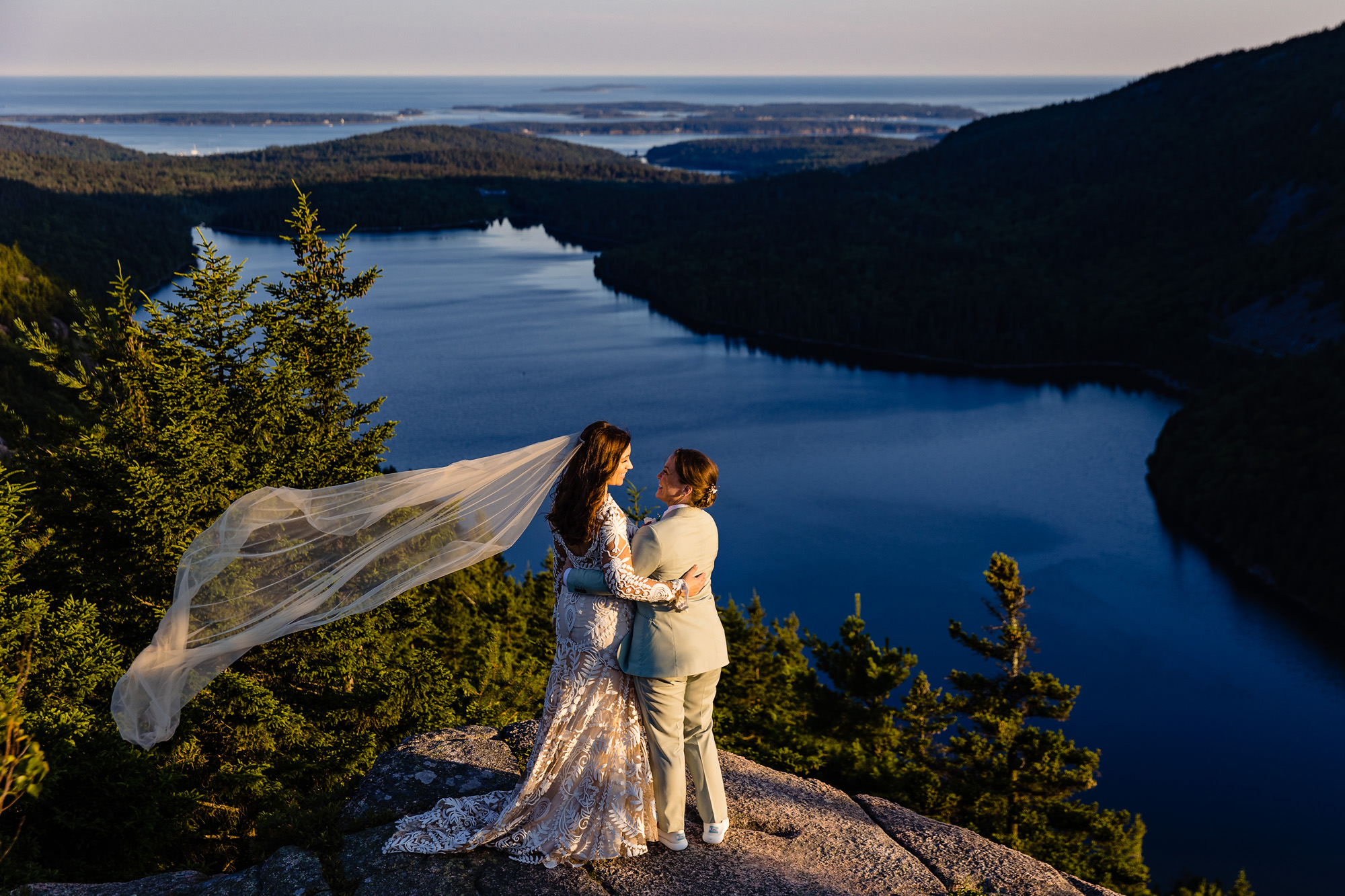 A wedding portrait of two brides on top of a mountain in Acadia.
