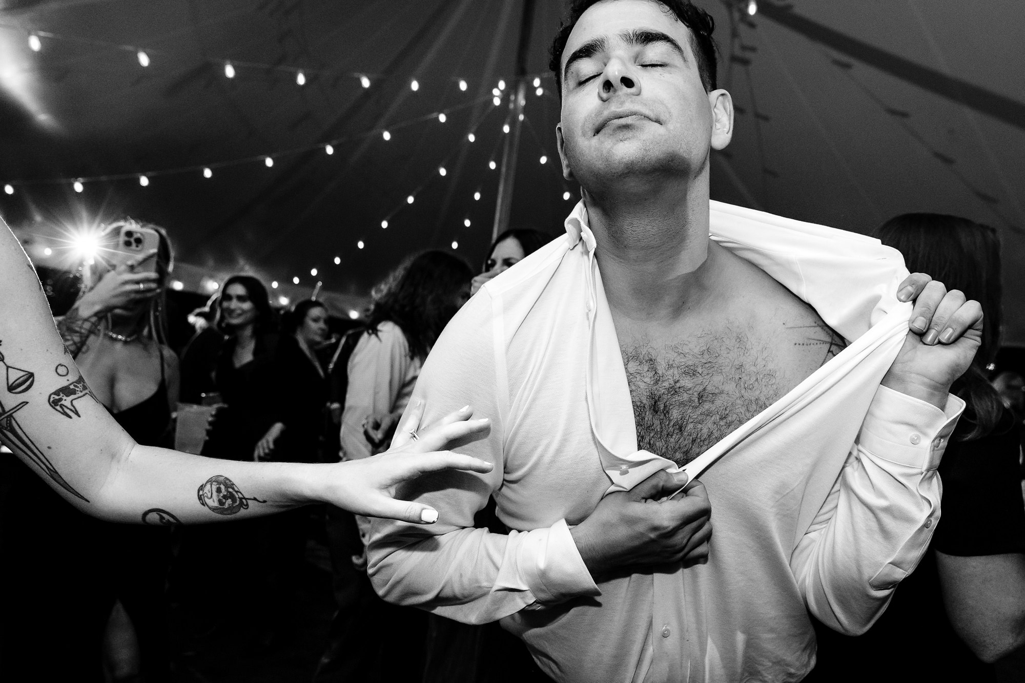 A groom takes off his shirt while dancing at his wedding.