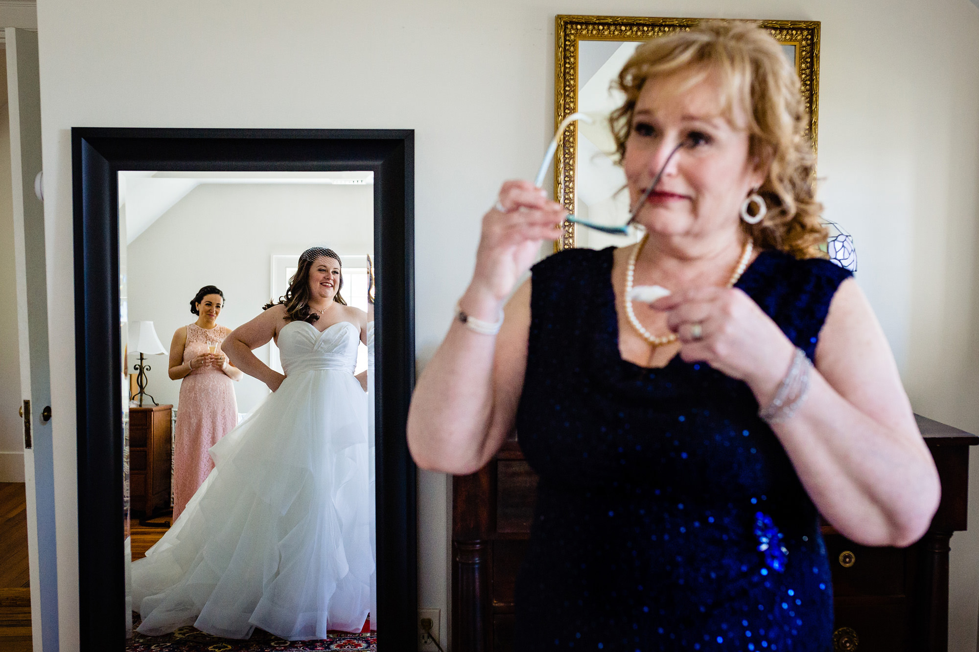 A mother of the bride cries as she sees her daughter in a wedding dress.