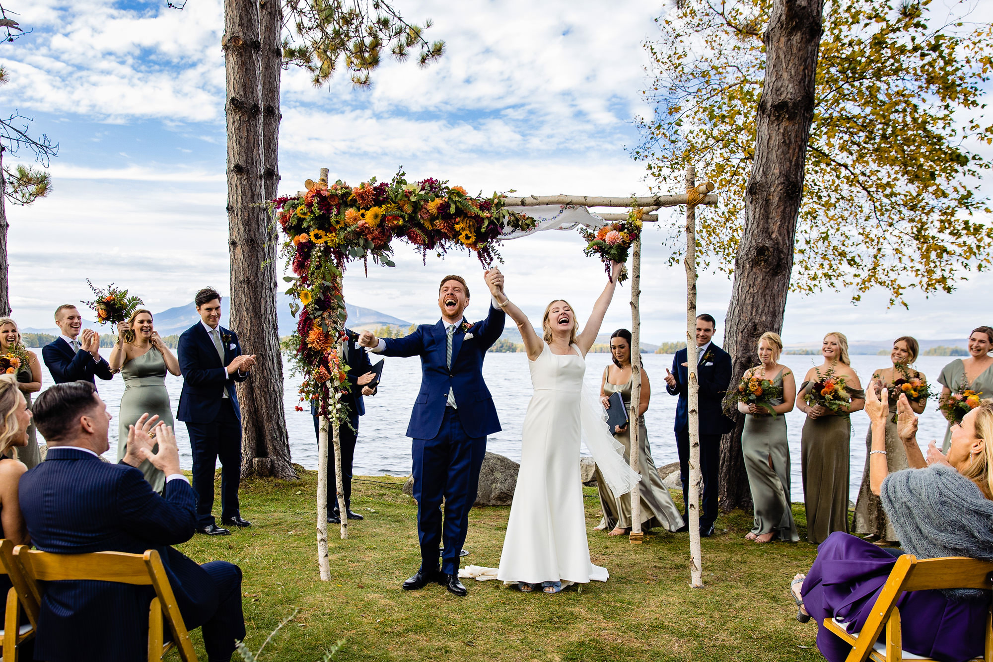A wedding couple raise their arms in celebration after being announced as married in front of their loved ones.