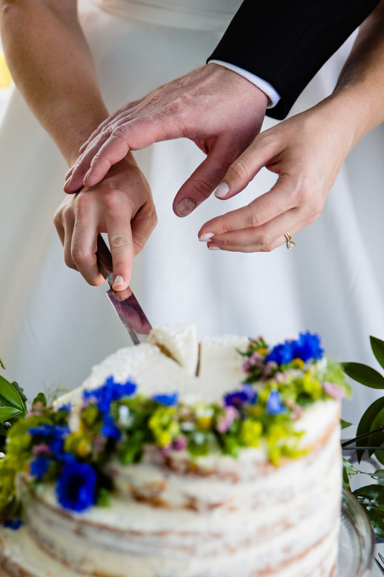 The hands of a wedding couple cutting their cake.