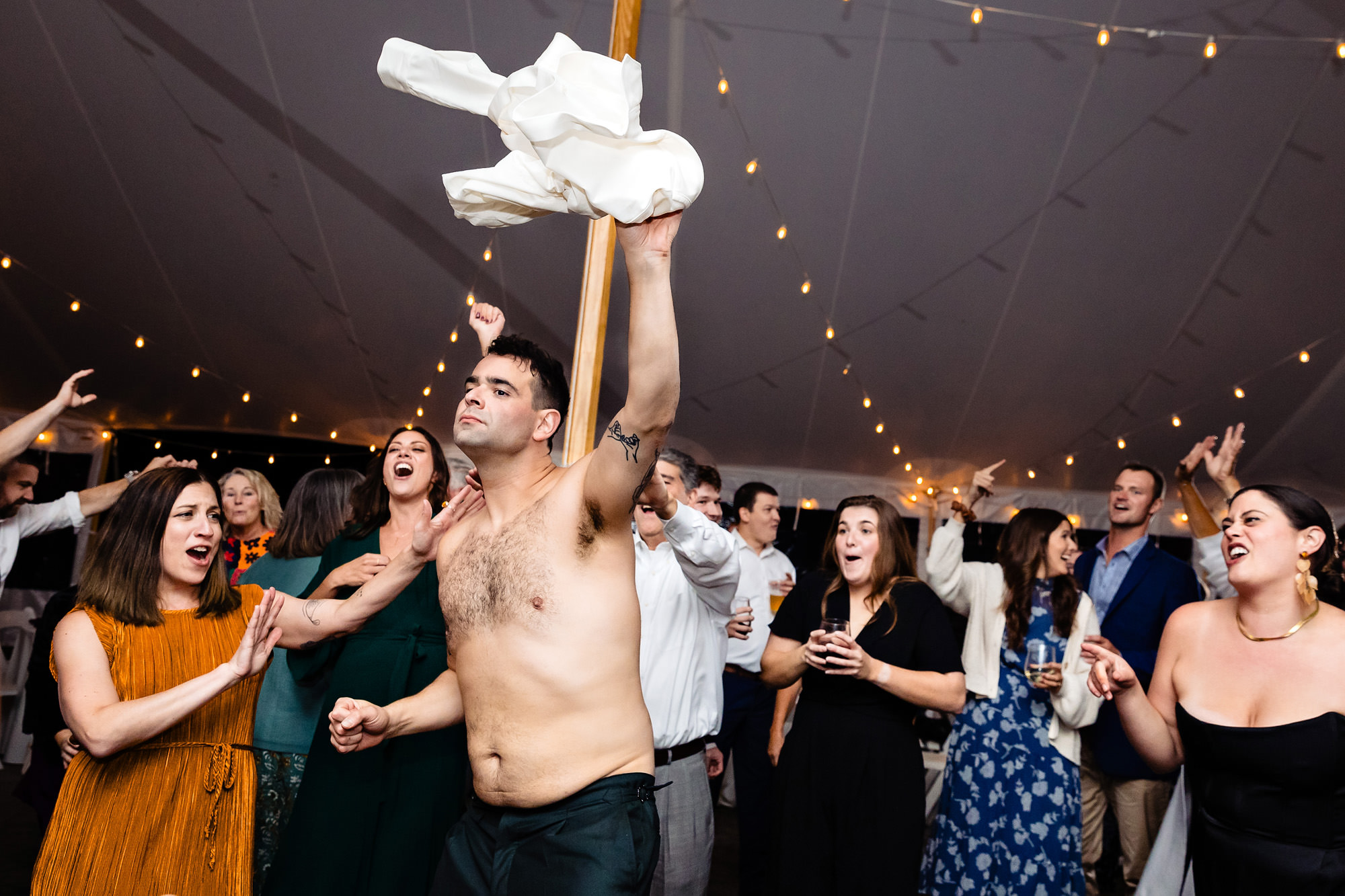 A groom takes off his shirt on the dance floor and guests react in shock and laughter.