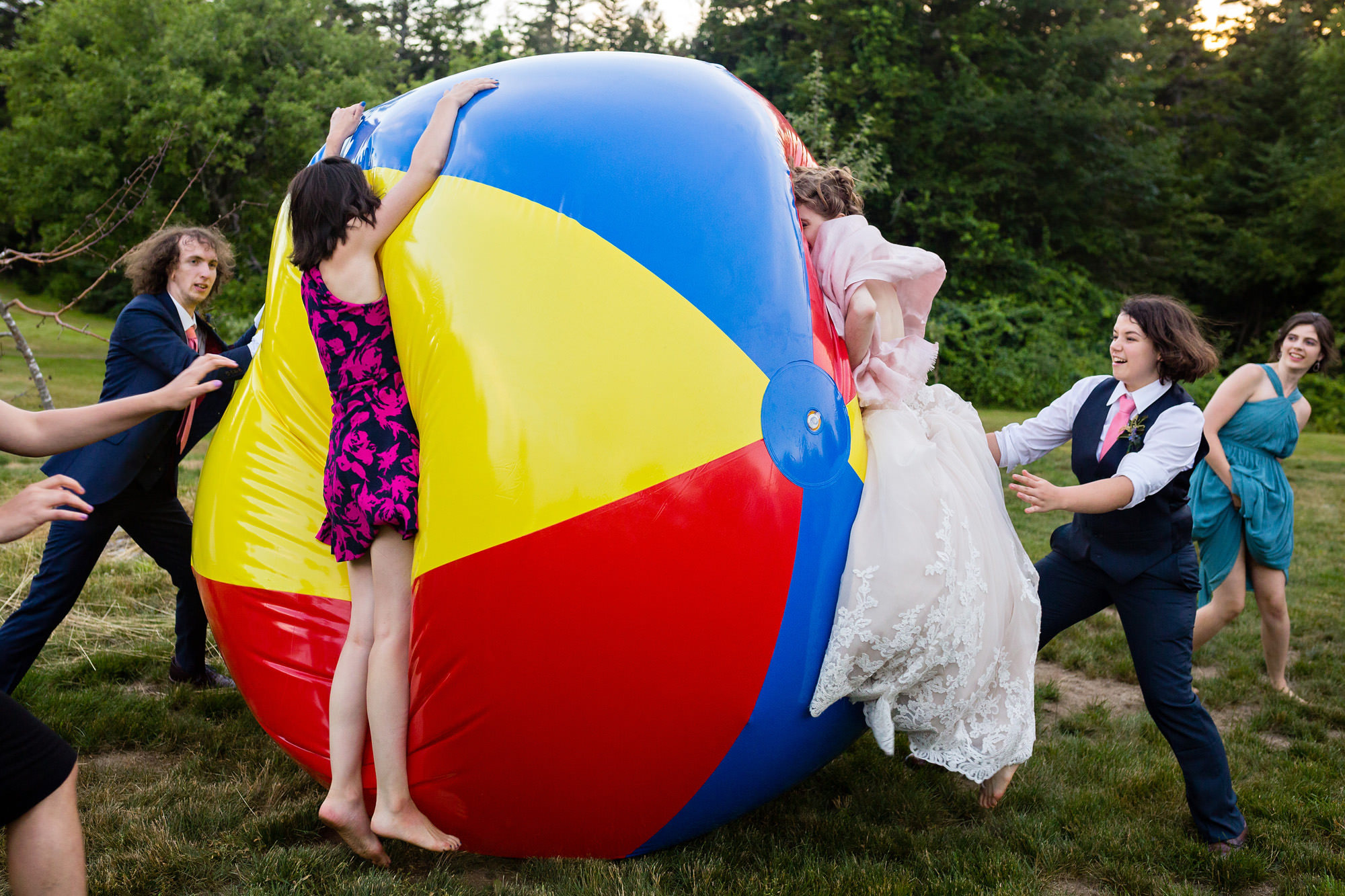 A wedding couple and their friends play with a giant beach ball during a wedding cocktail hour.