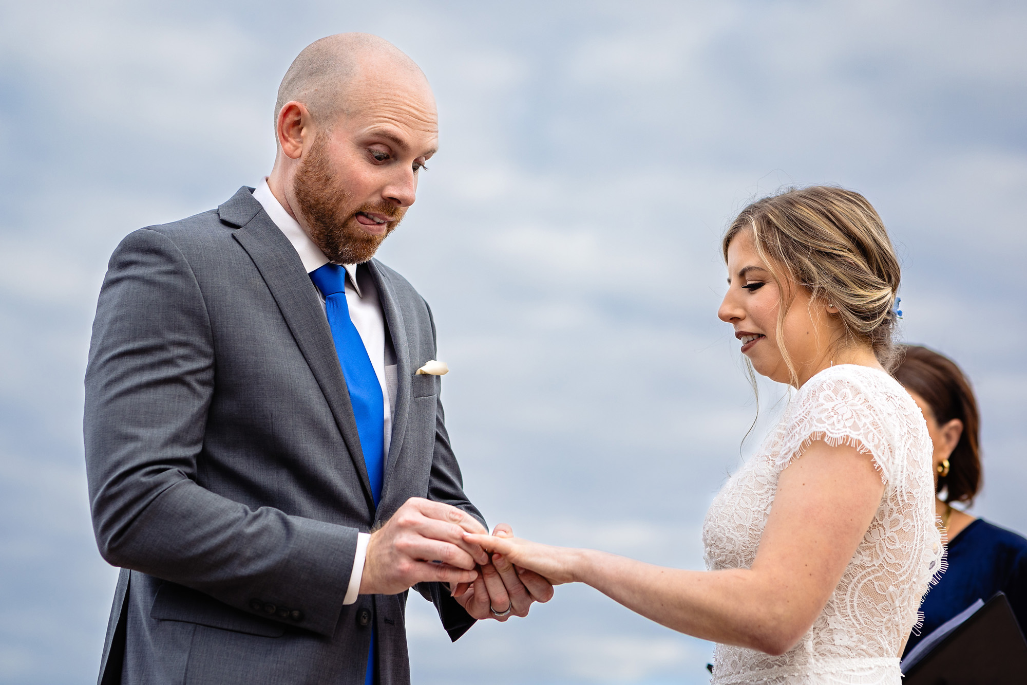 A groom struggles with sliding the ring on the bride's finger during their elopement ceremony.