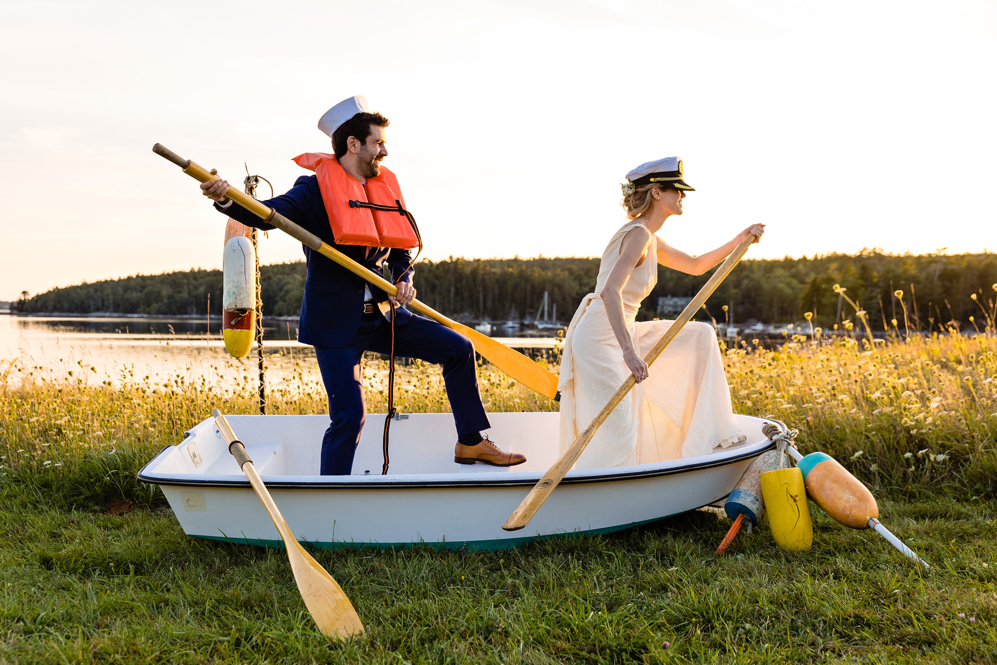 A wedding couple pose in a rowboat for a portrait.