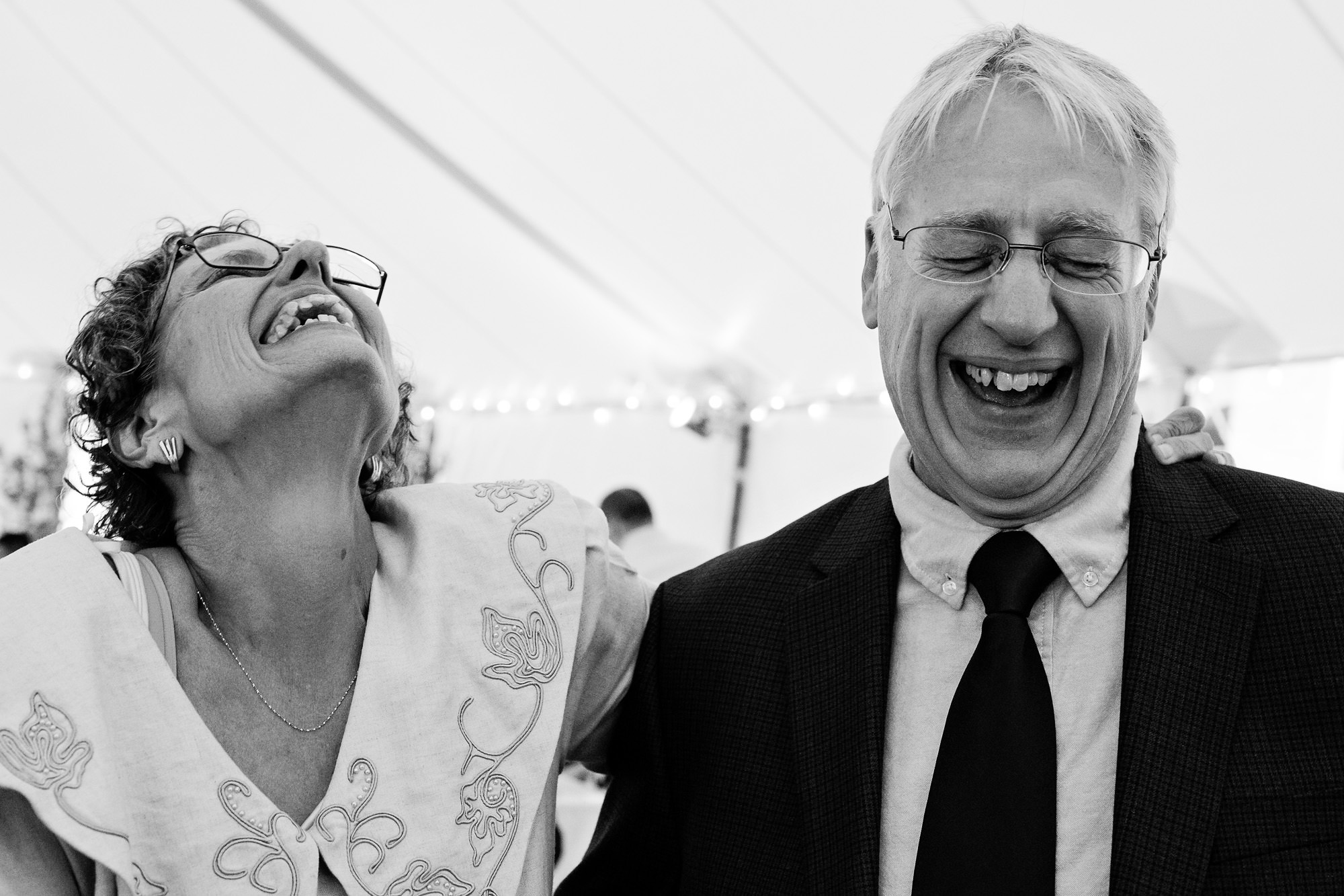 Older family members laugh on the dance floor at a wedding.,