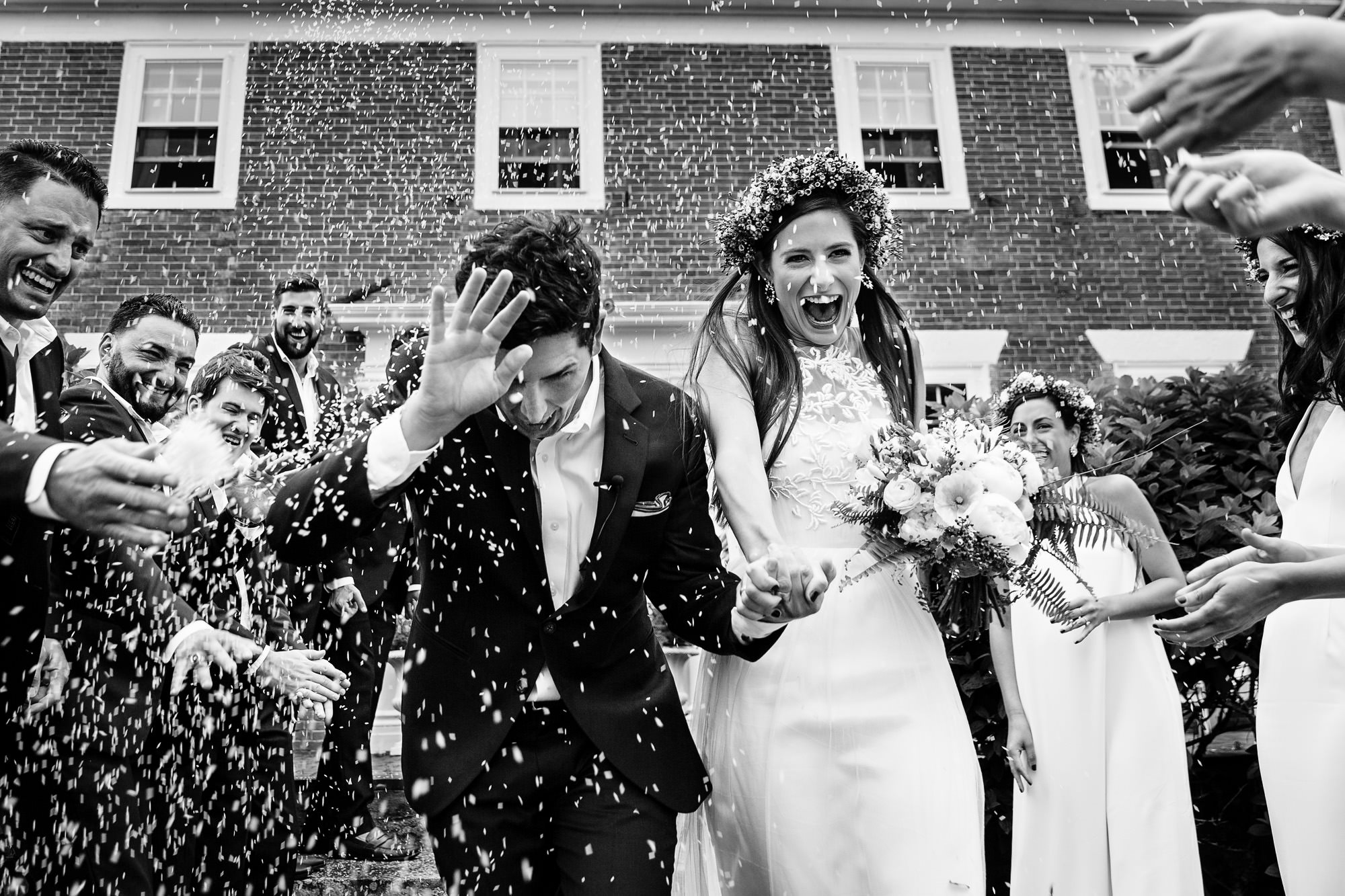 A bride and groom exits their wedding ceremony while rice is thrown at them.