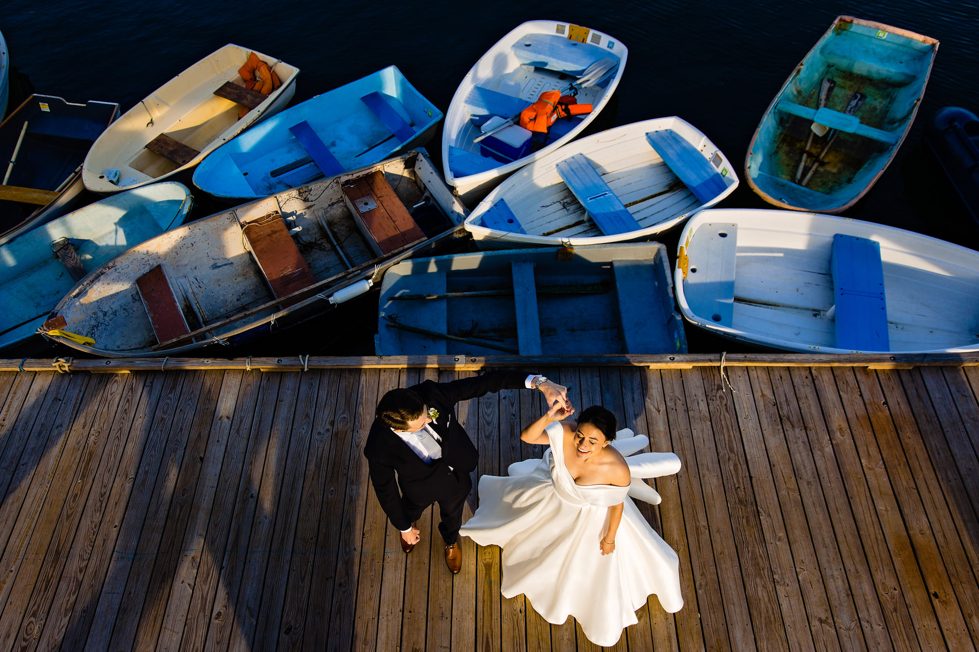 A wedding couple dance on a dock at sunset.