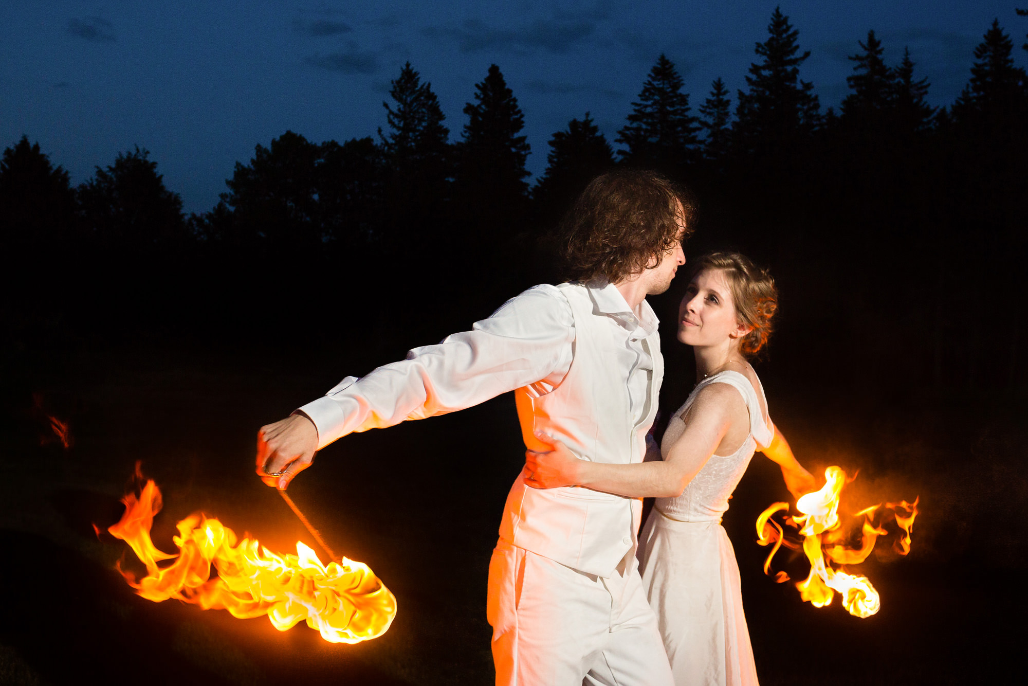 A wedding couple does a fire dance at their wedding at twilight.