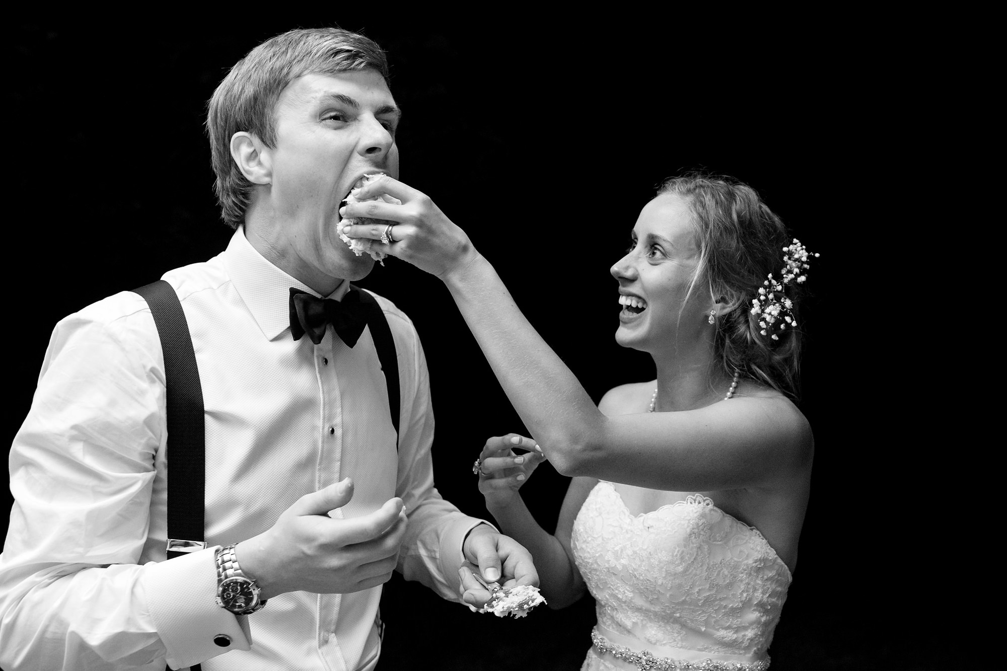 The bride shoves cake into the groom's face at their wedding.