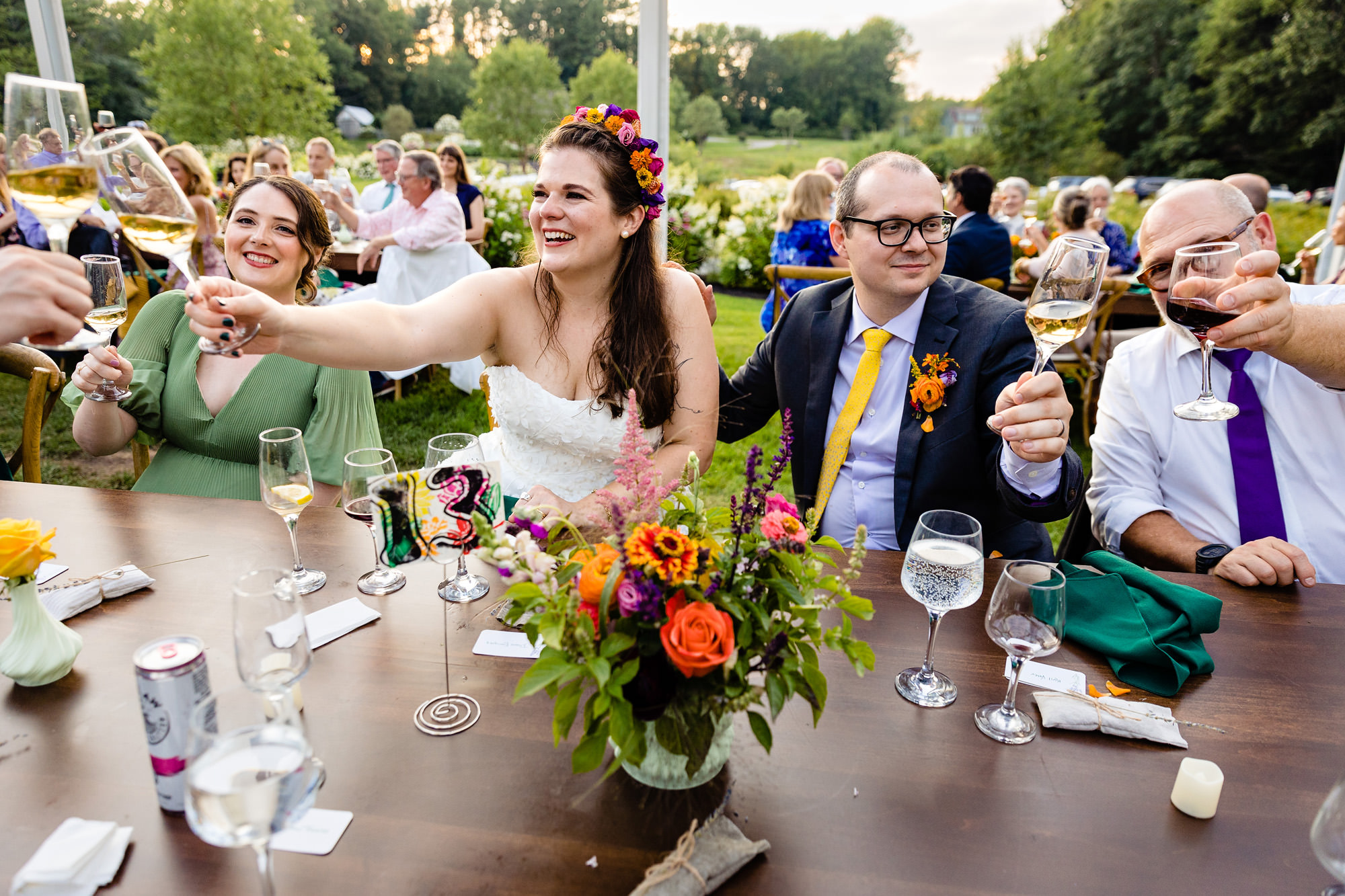 A wedding couple clink their glasses with their loved ones during toasts.