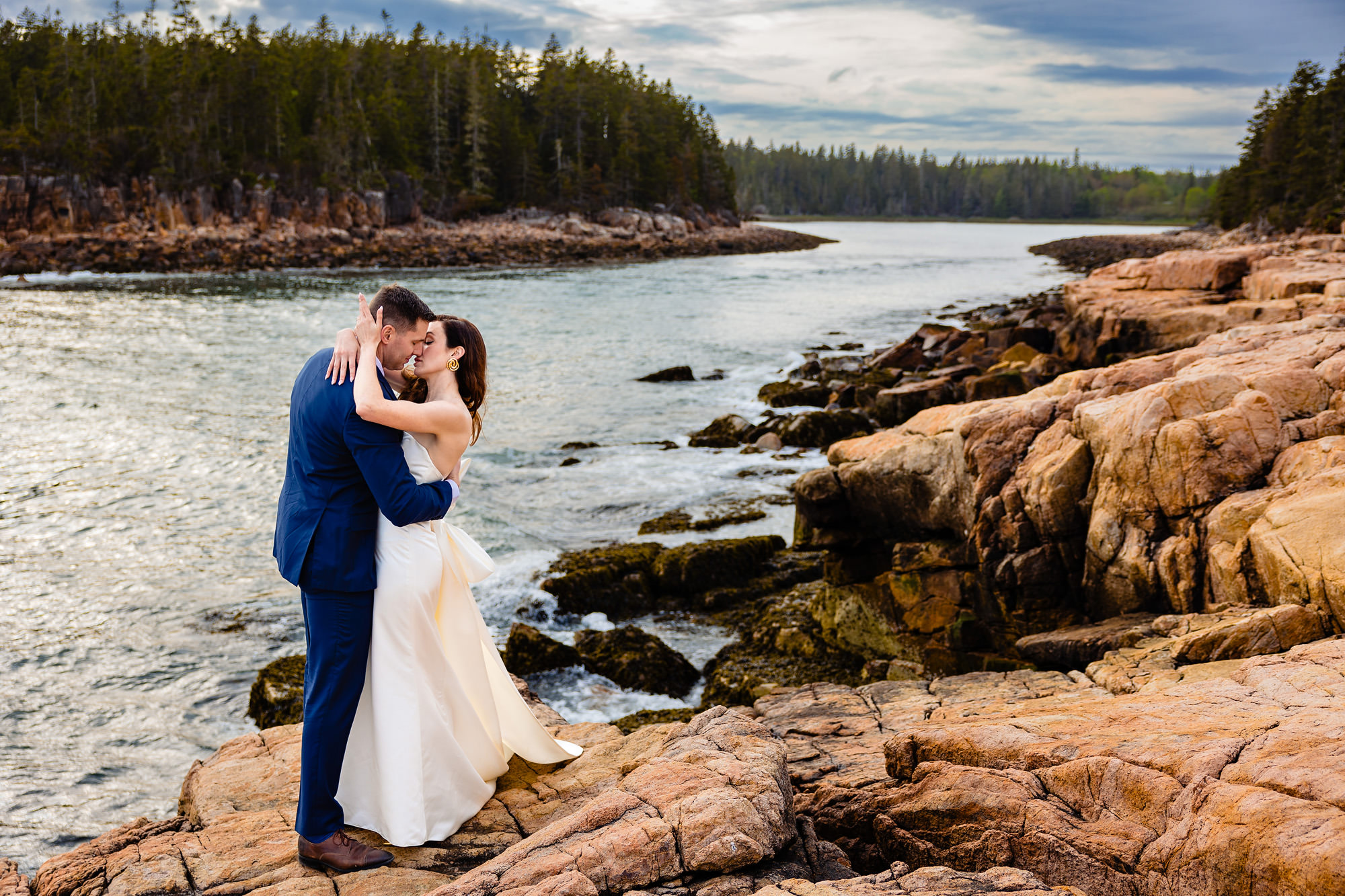 A bride and groom kiss on the cliffs of Acadia National Park