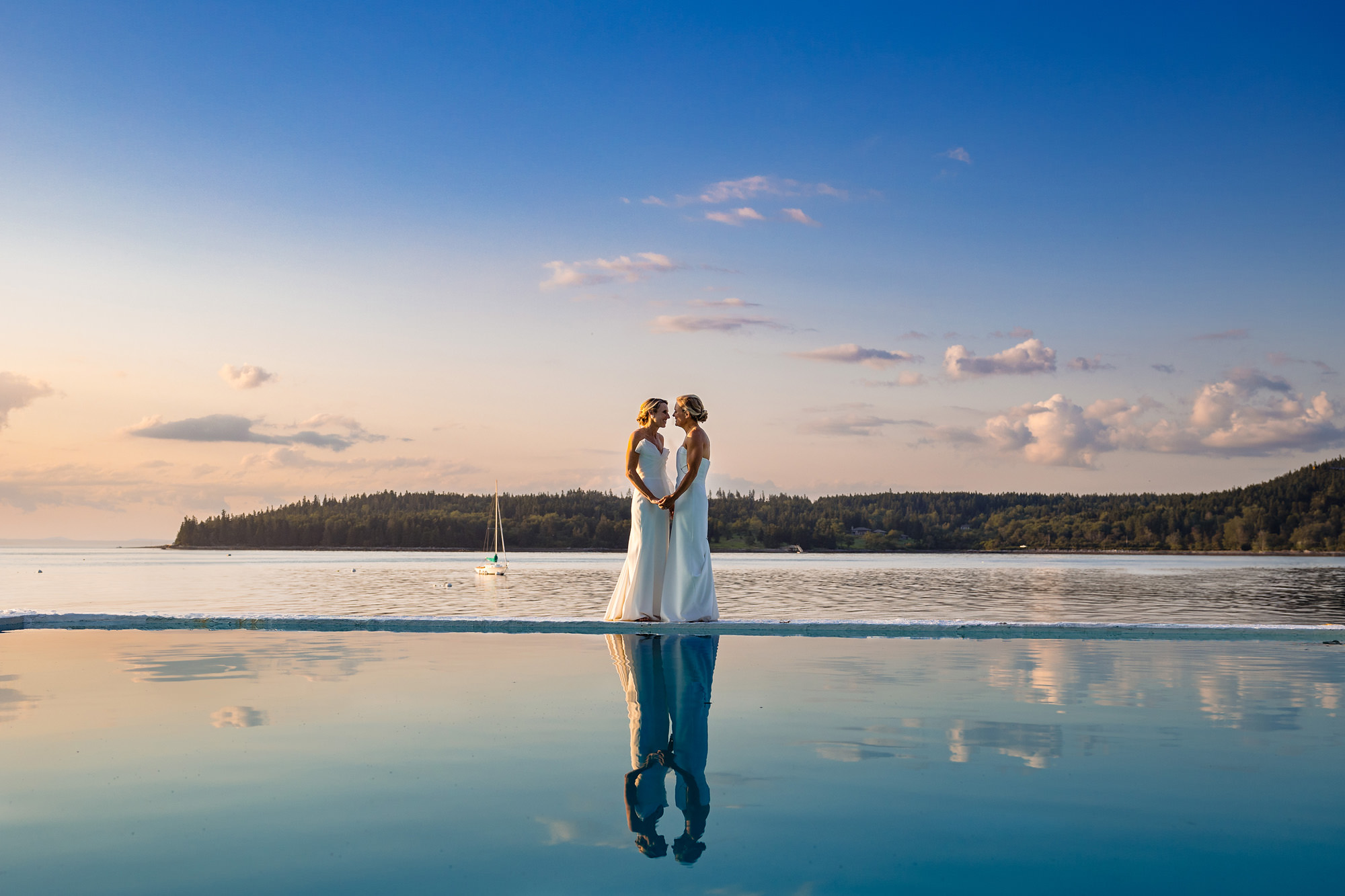 Two brides pose at the edge of a salt water pool at sunset at a MDI wedding